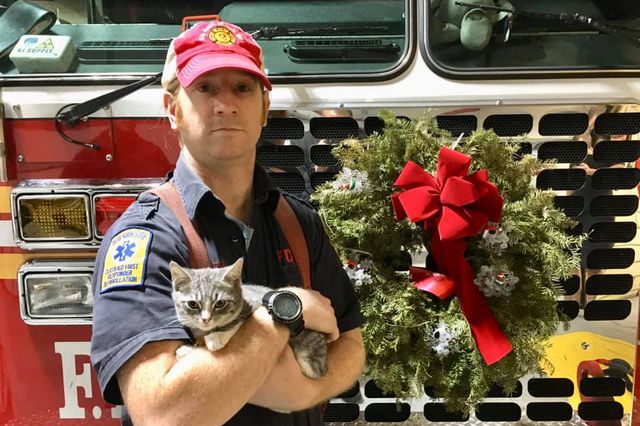 Firefighter David Wiwczar with Franklin, posing in front of a fire truck with a wreath on it